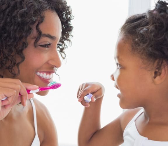 Mother showing her daughter how to brush her teeth